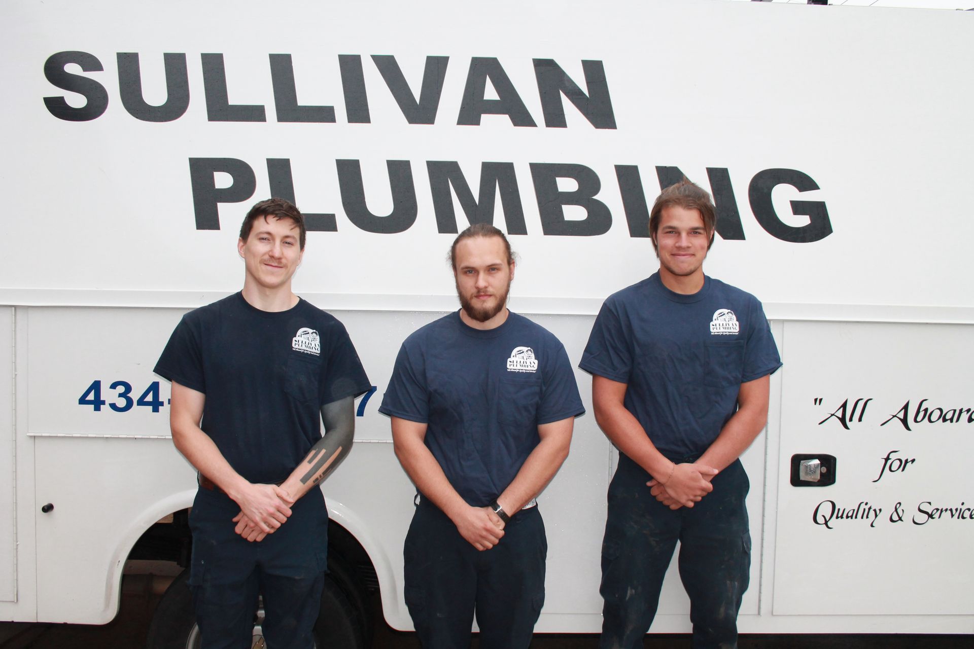 Three men standing in front of a truck that says sullivan plumbing
