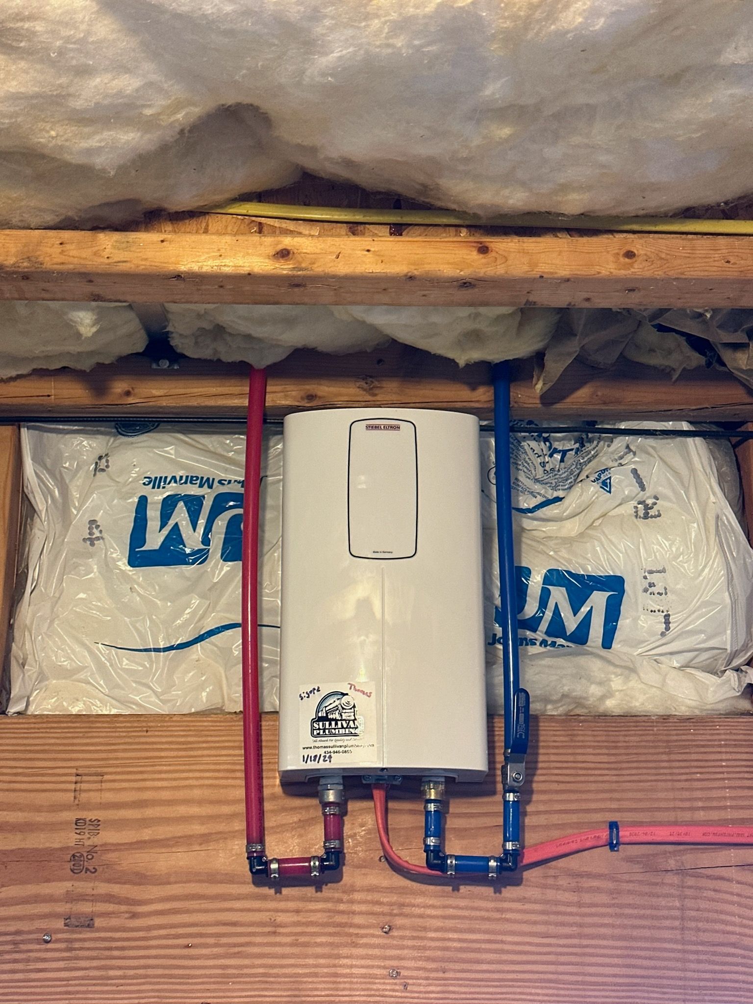 A white water heater is hanging from the ceiling in a room.
