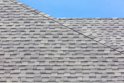 Gray shingled roof with a diagonal ridge beneath a blue sky