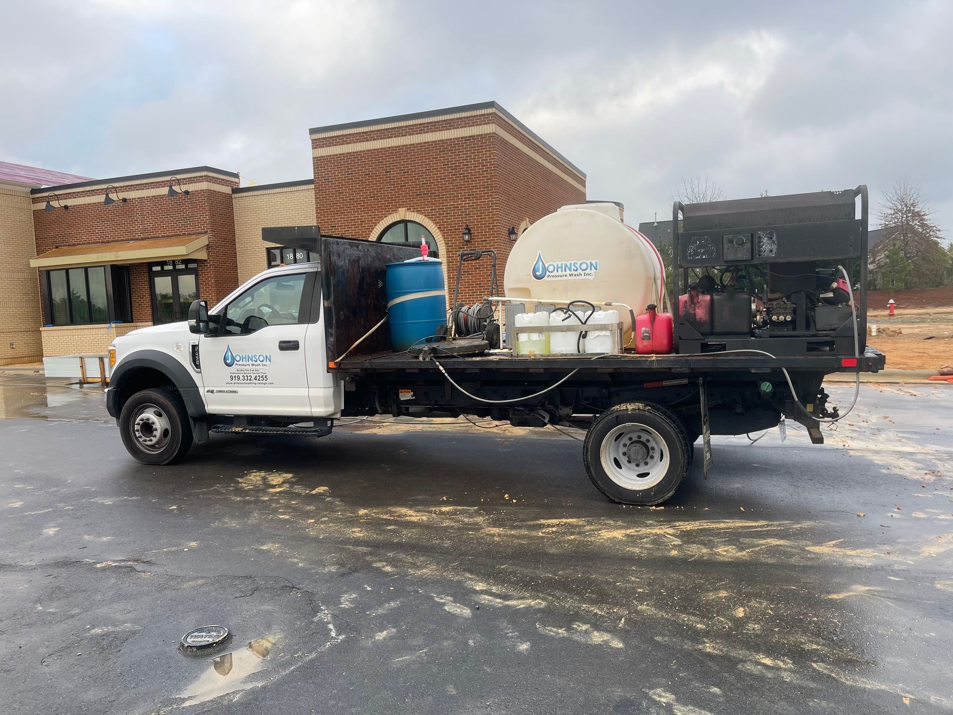 A white truck is parked in a parking lot in front of a building.