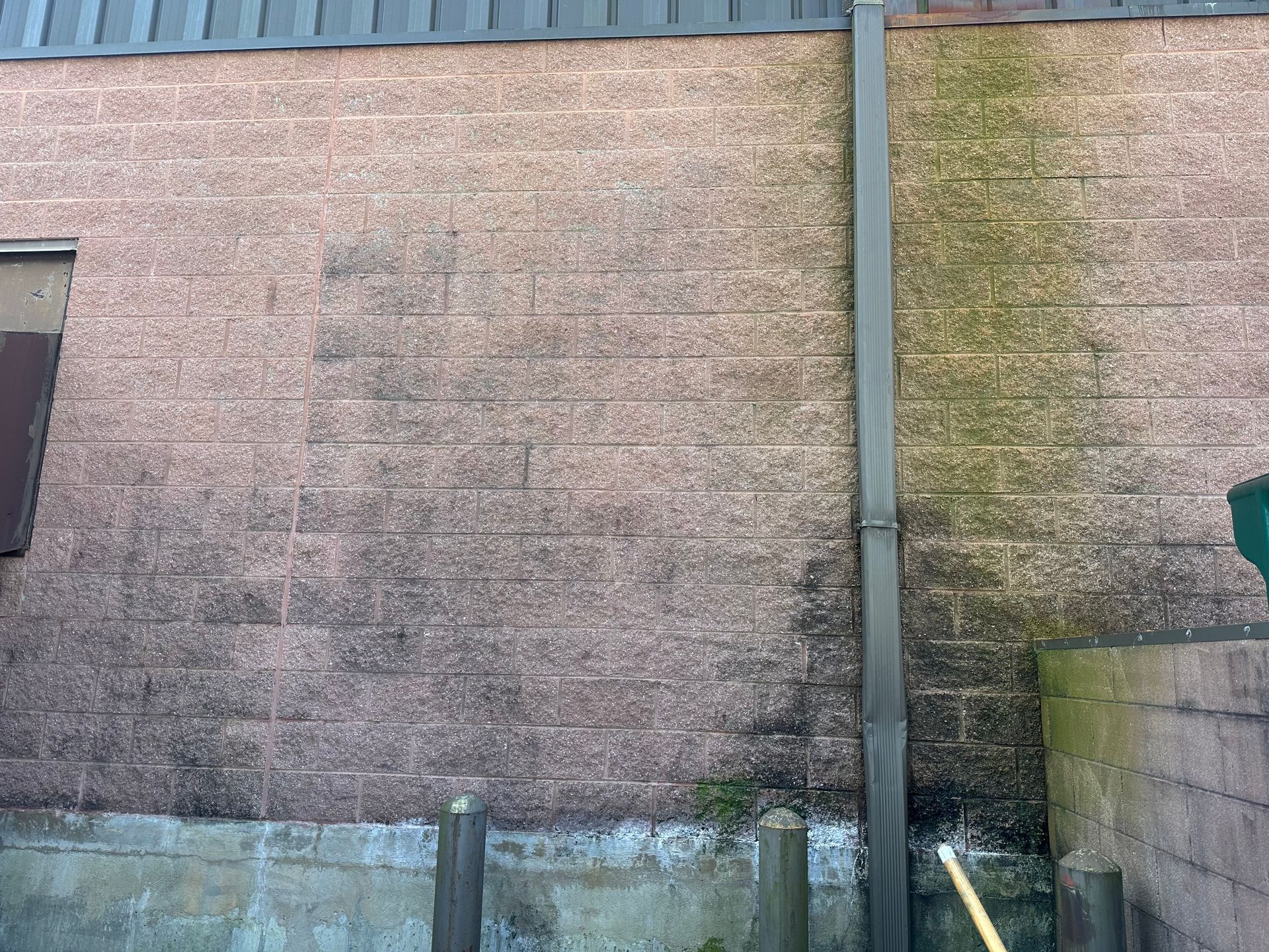 a brick wall with moss growing on it and a drain pipe.