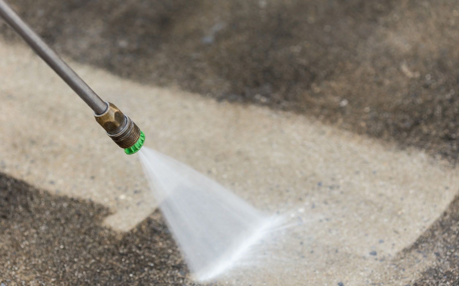 A person is using a high pressure washer to clean a concrete floor.
