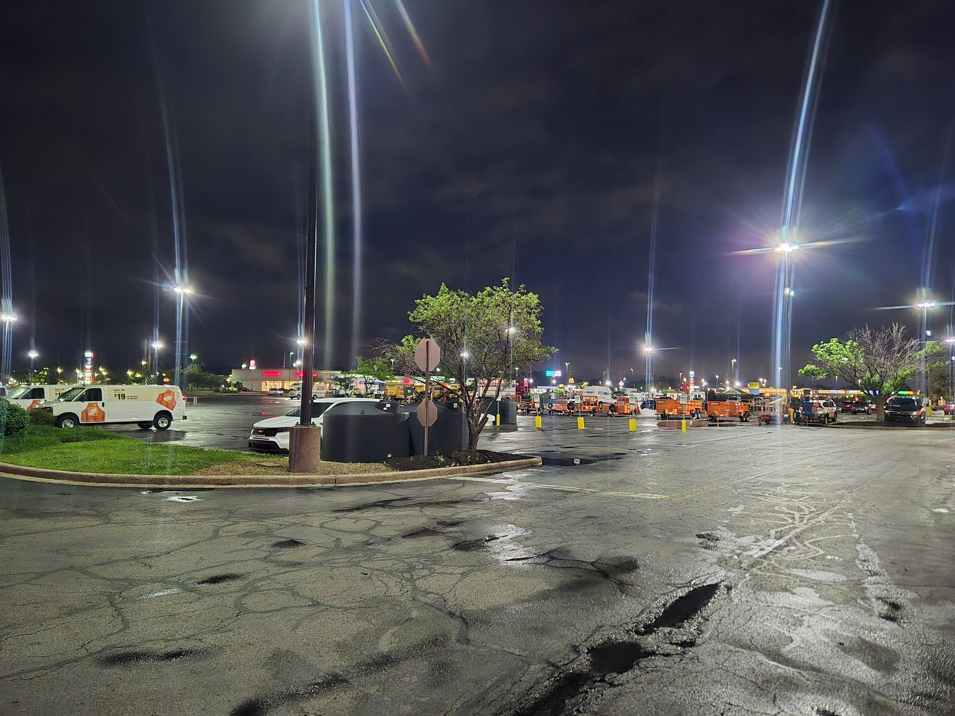 Night scene of a parking lot with damaged cars, emergency vehicles, and a crowd; possibly an accident scene.