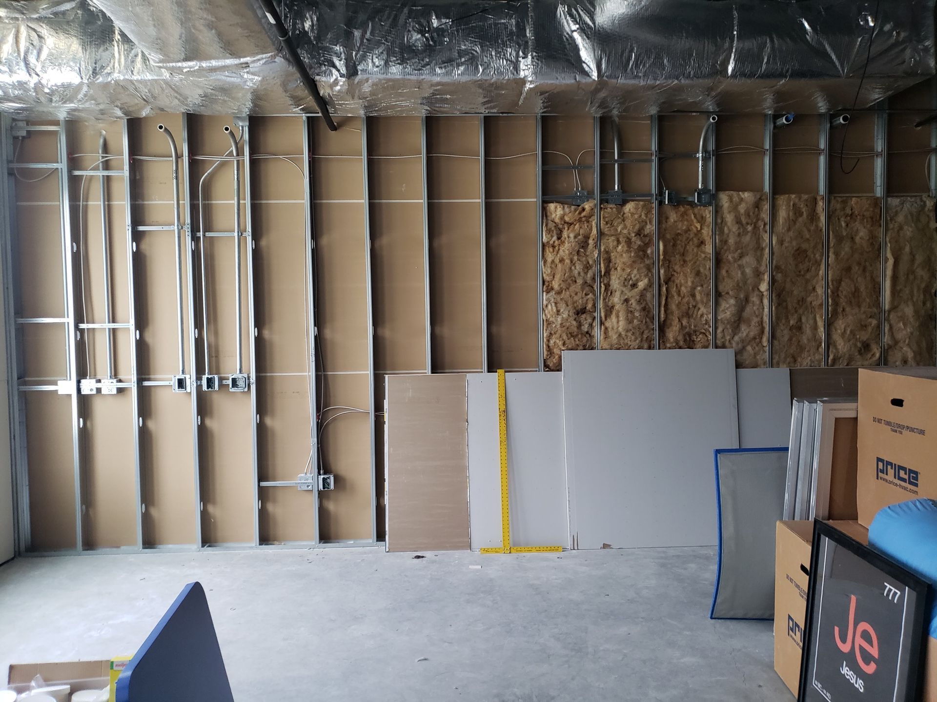 Interior construction site with exposed framing, insulation, and drywall.