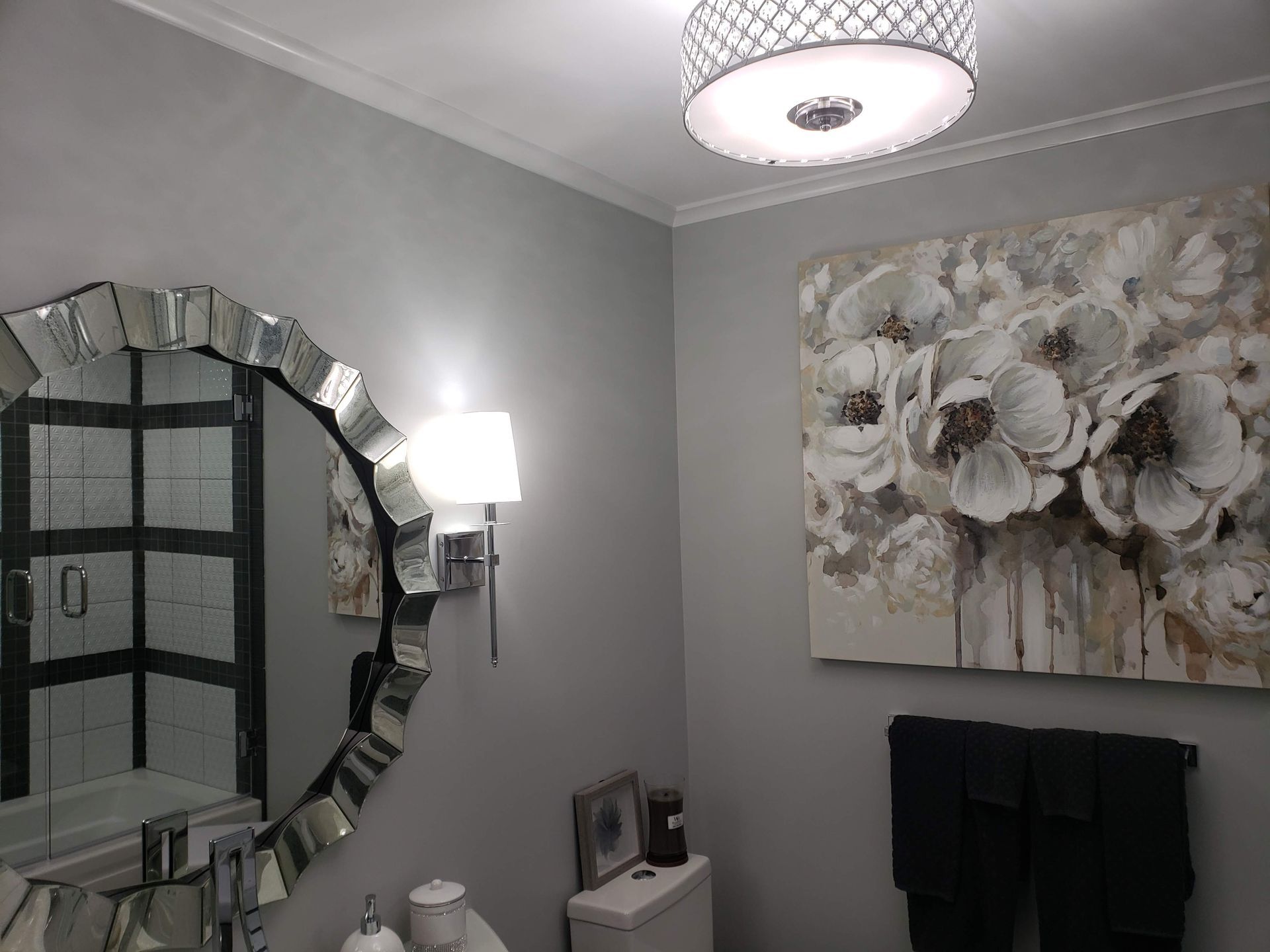 Bathroom with a decorative mirror, floral artwork, and gray walls.