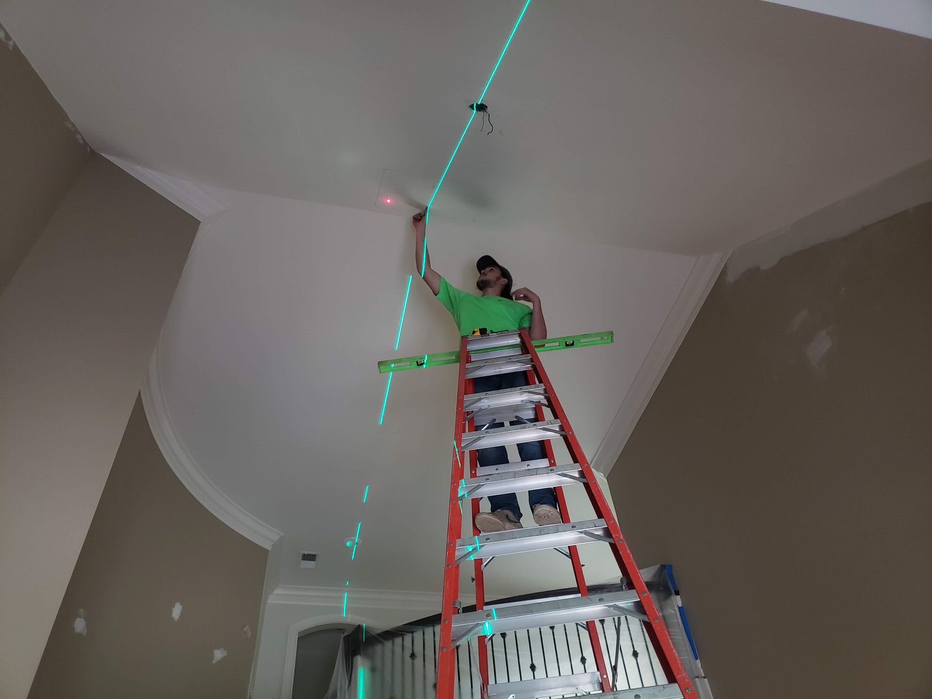 Person on a ladder, using a laser level to mark the ceiling in a room.