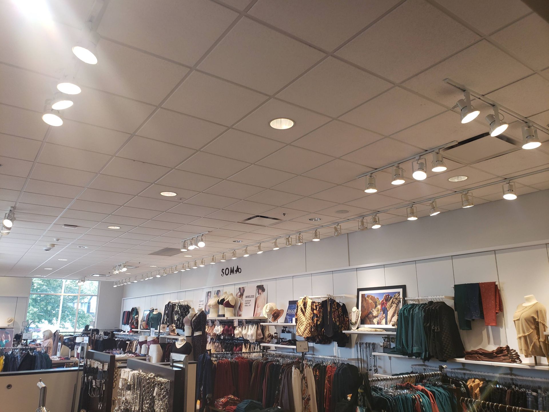 Clothing store interior with clothing racks, bright lighting, and white walls.