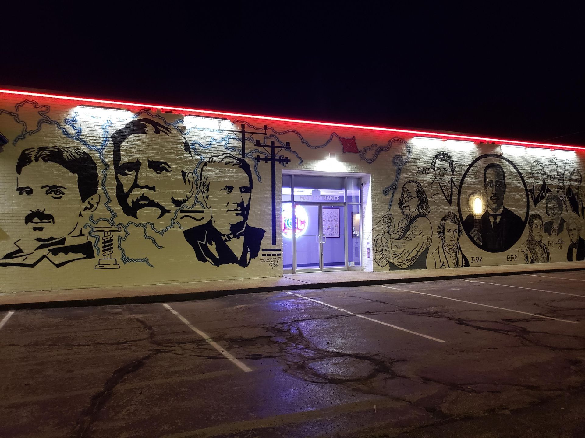 Mural of black and white historical figures on a building exterior with red neon lights above entrance at night.