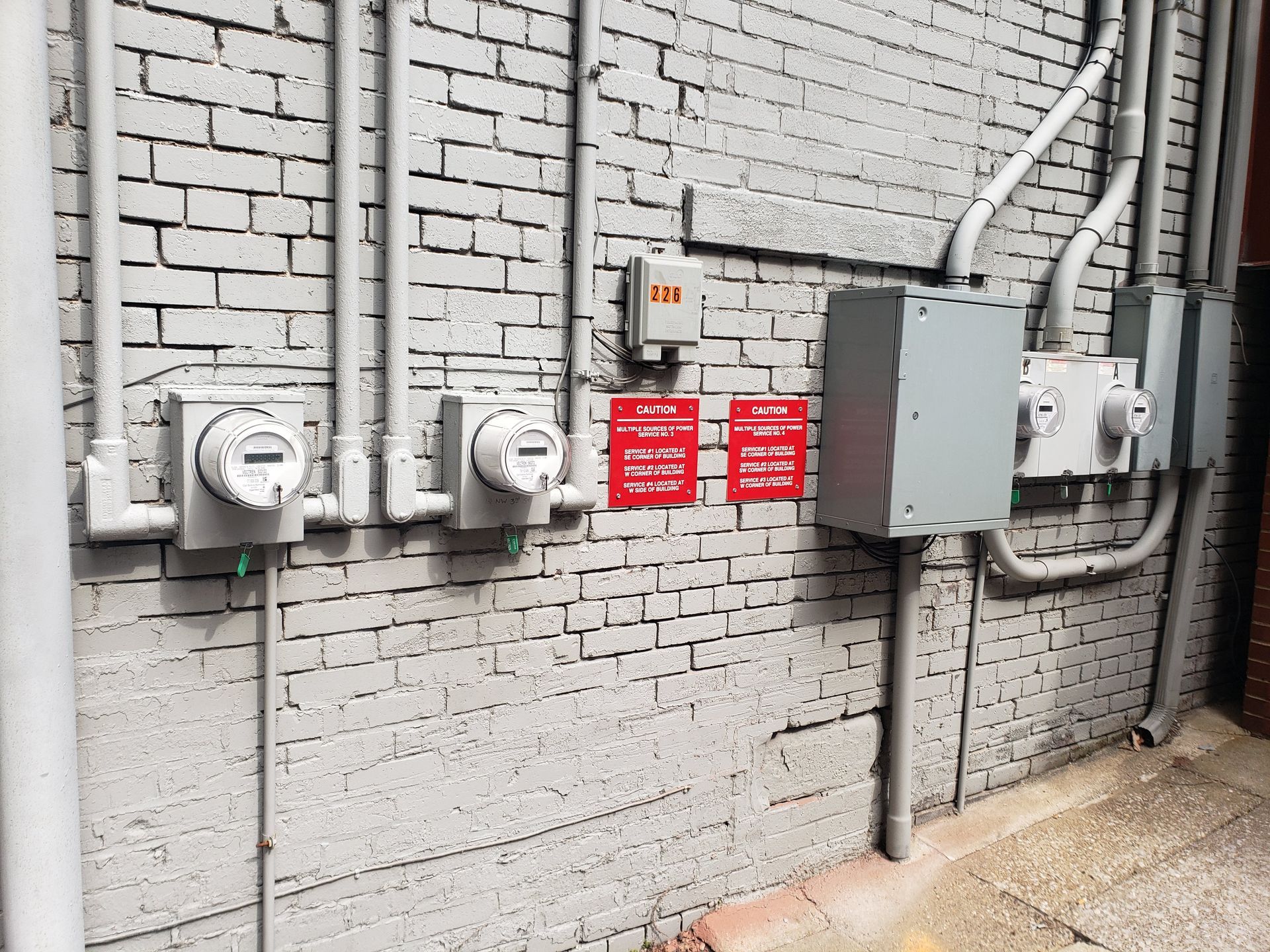 Electrical boxes and conduits on a gray brick wall.
