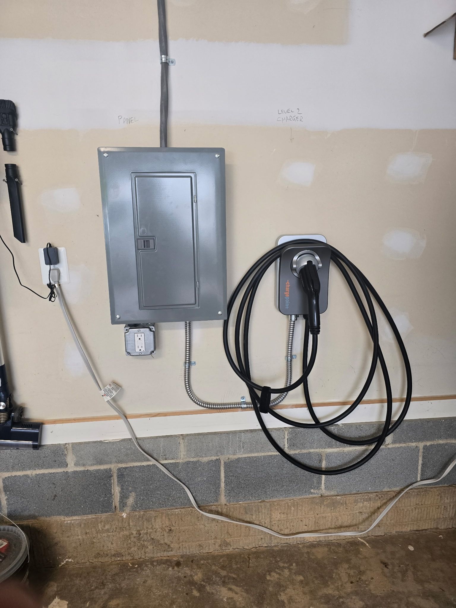 An electric car charger is attached to a wall in a garage.