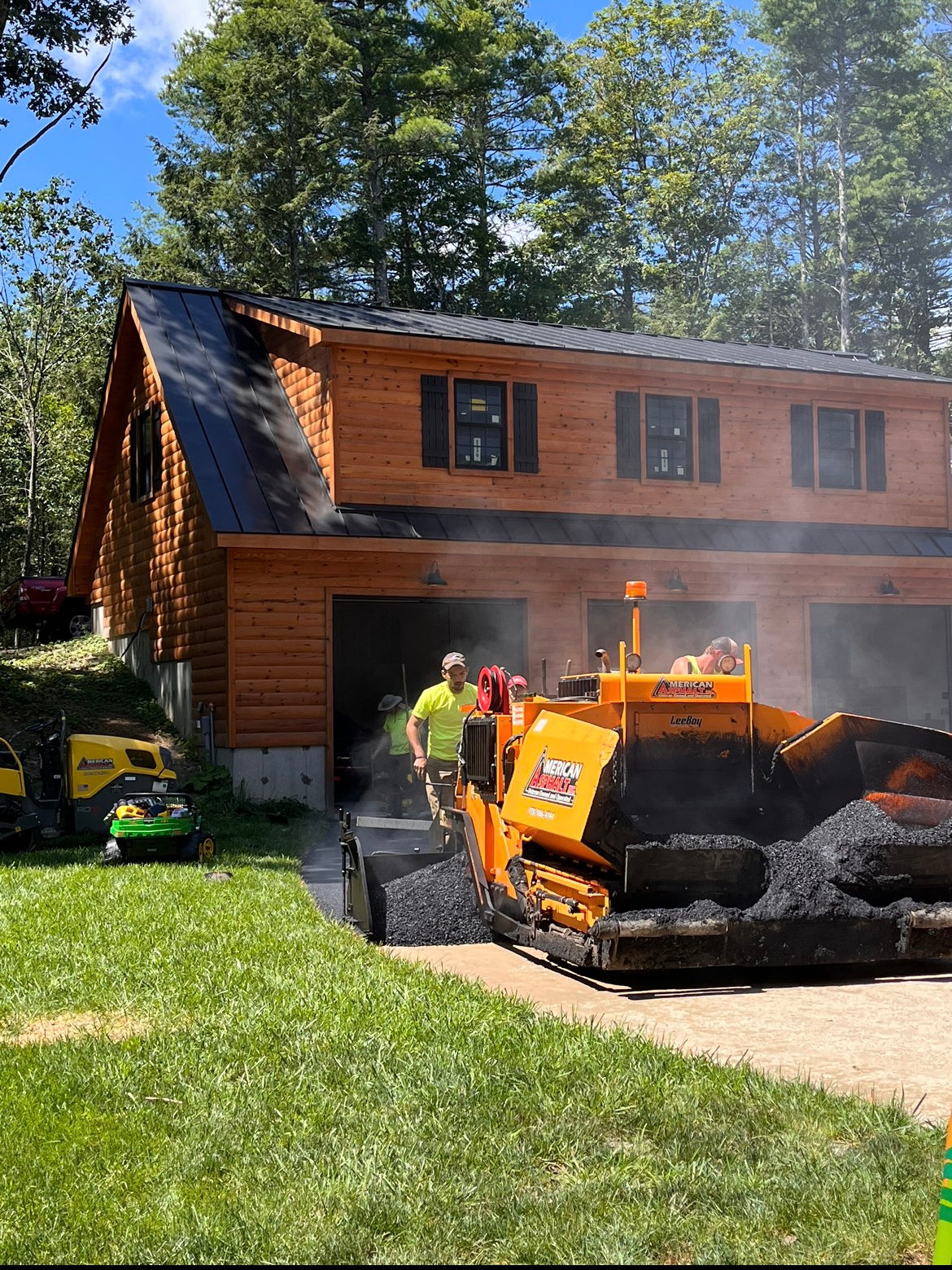 A tractor is paving a driveway in front of a house.
