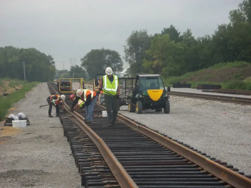 A group of construction workers are working on train tracks