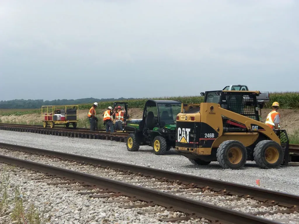 A group of construction workers are working on train tracks.