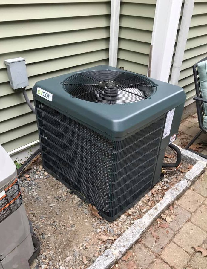 A large air conditioner is sitting on the side of a house.