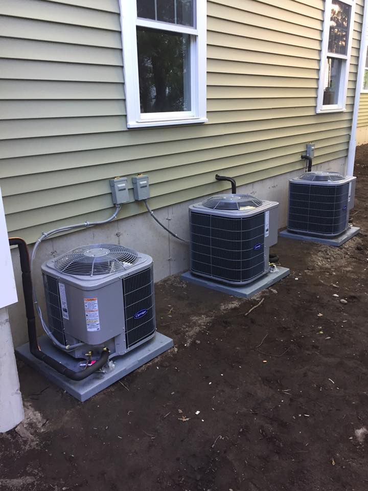 Three air conditioners are sitting on the side of a house.