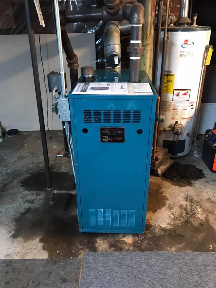 A blue boiler is sitting in a basement next to a water heater.