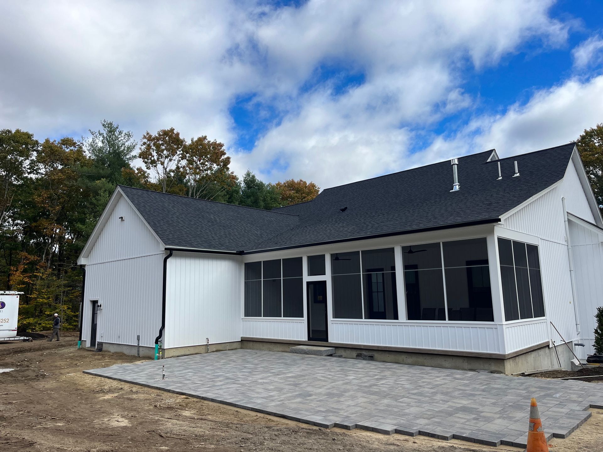 White single-story house under construction with a dark roof and unfinished front patio area
