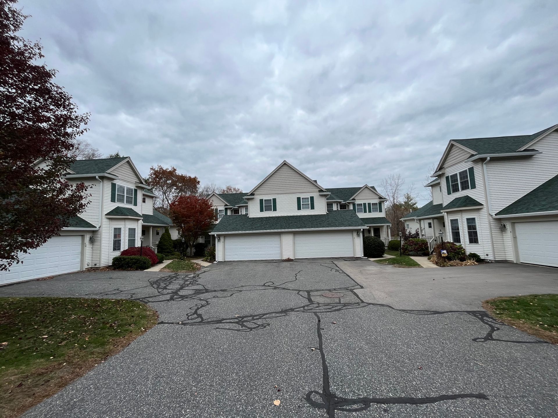 Suburban cul-de-sac with houses, cracked asphalt, and cloudy sky