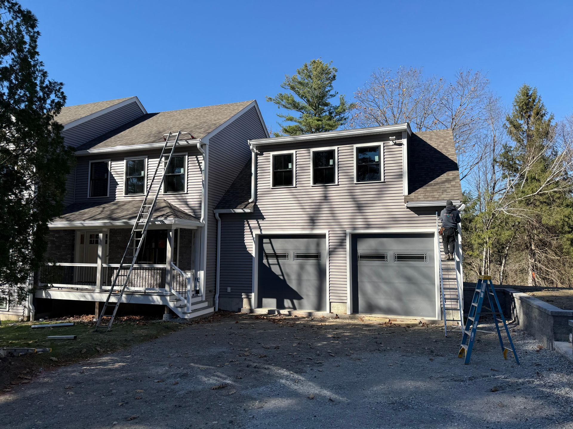 Two-story house under renovation with plywood siding, garage, and trees in front yard