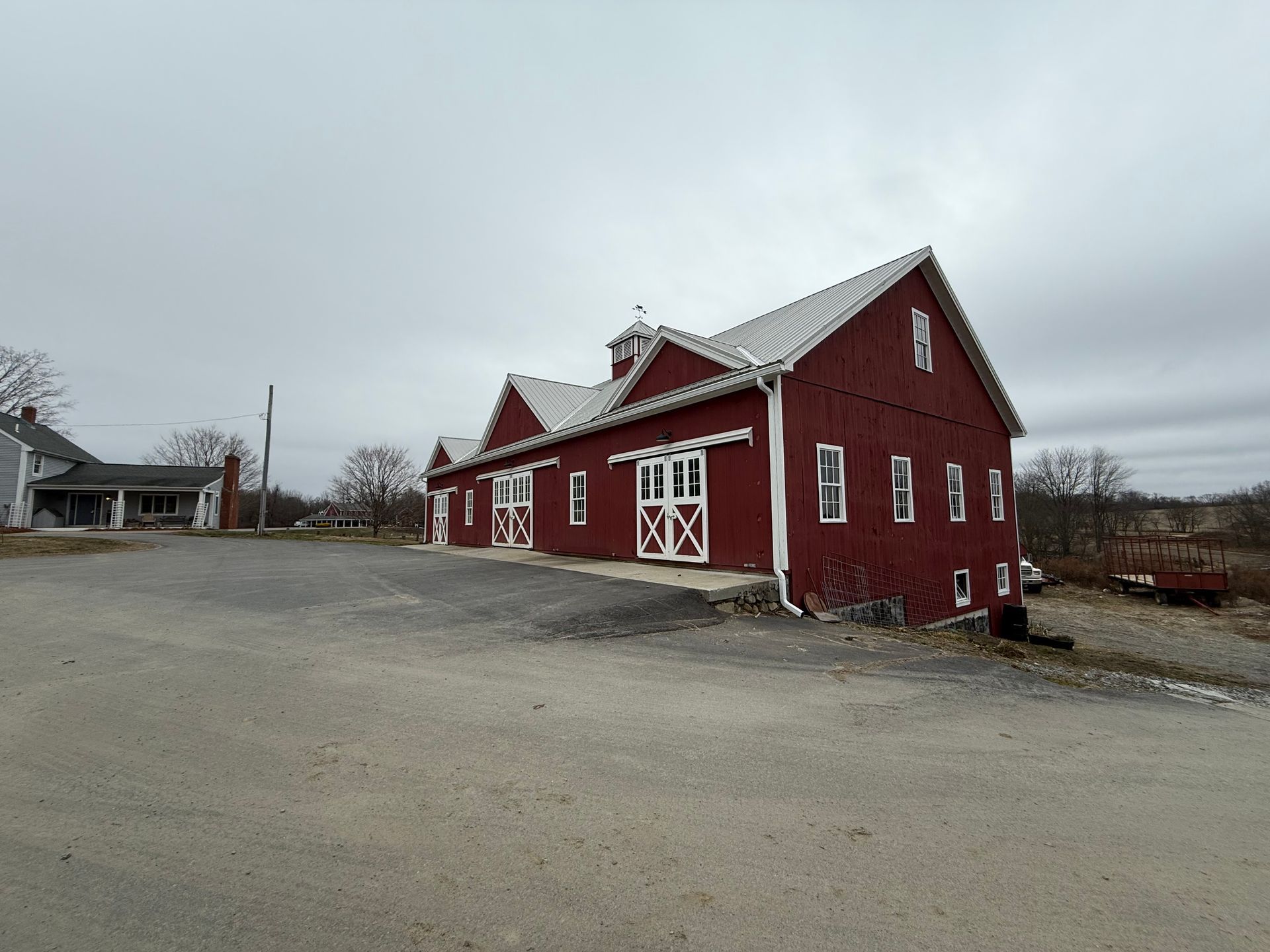 Red barn-style building with white trim beside a gravel lot under an overcast sky