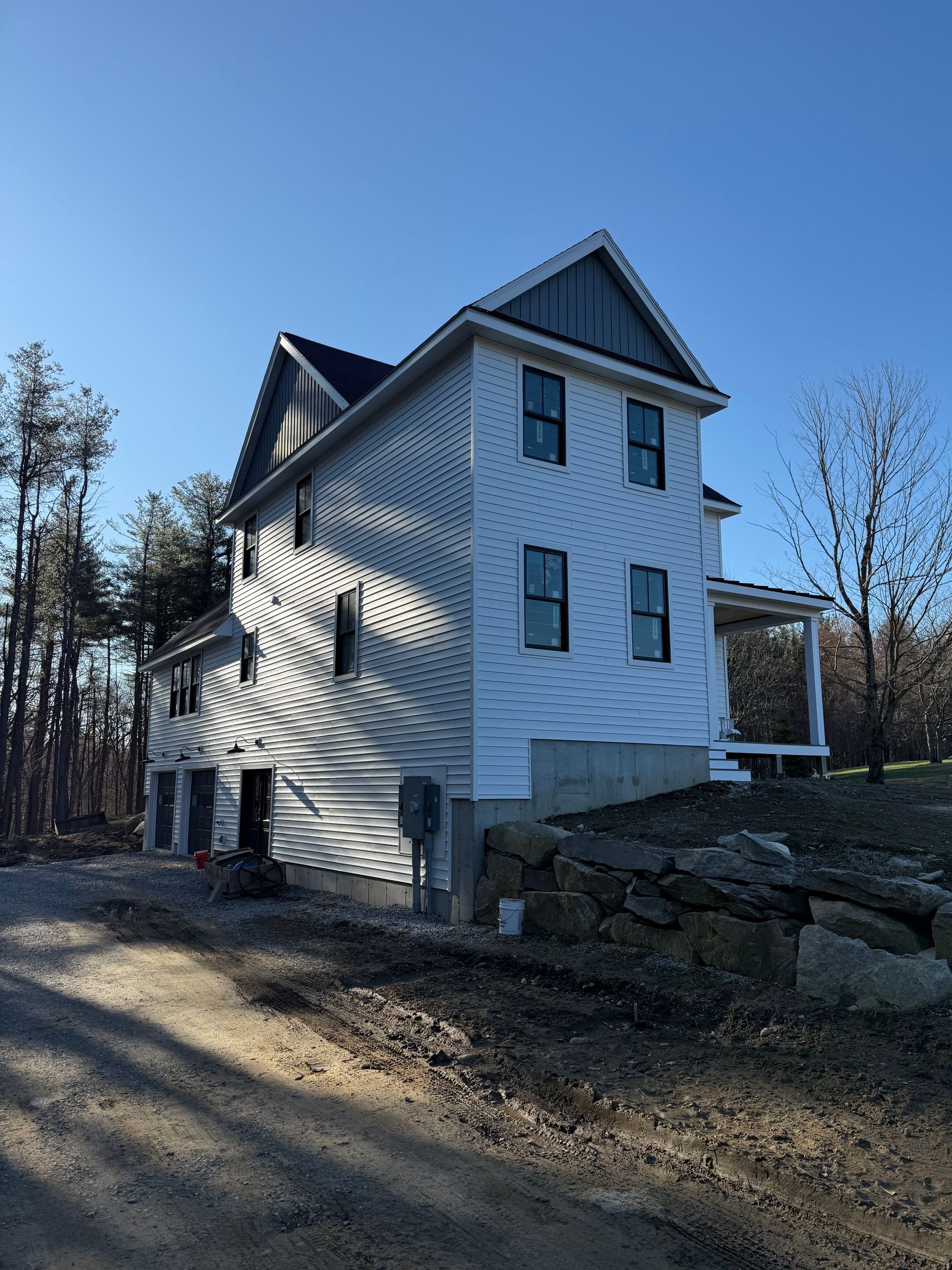 White wooden house with steep roof on a rocky hillside under a clear blue sky