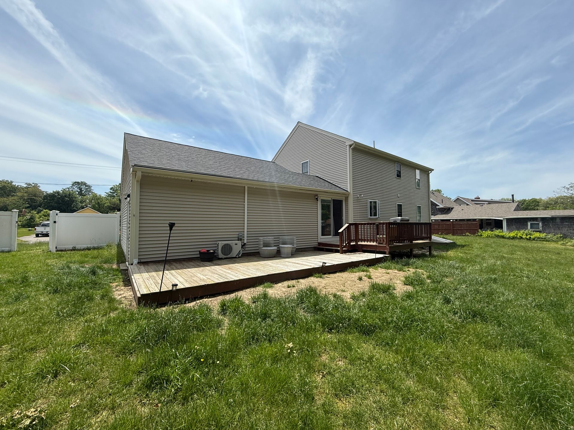 Backyard deck with a ramp attached to a house, beside a grassy yard under a blue sky