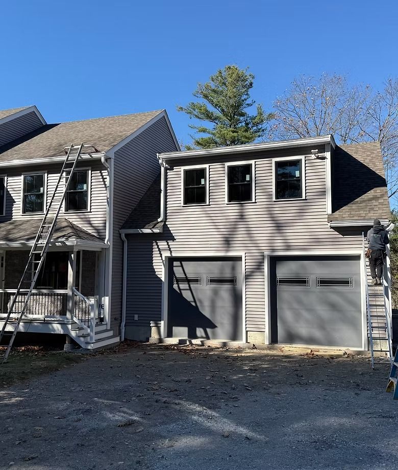 Gray two-story house with attached two-car garage and small front porch under clear blue sky