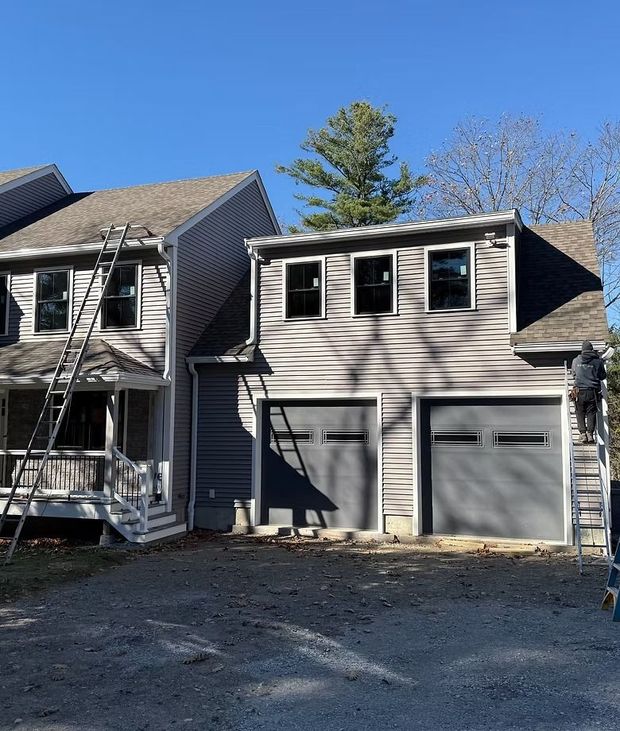 Gray two-story house with attached two-car garage and small front porch under clear blue sky