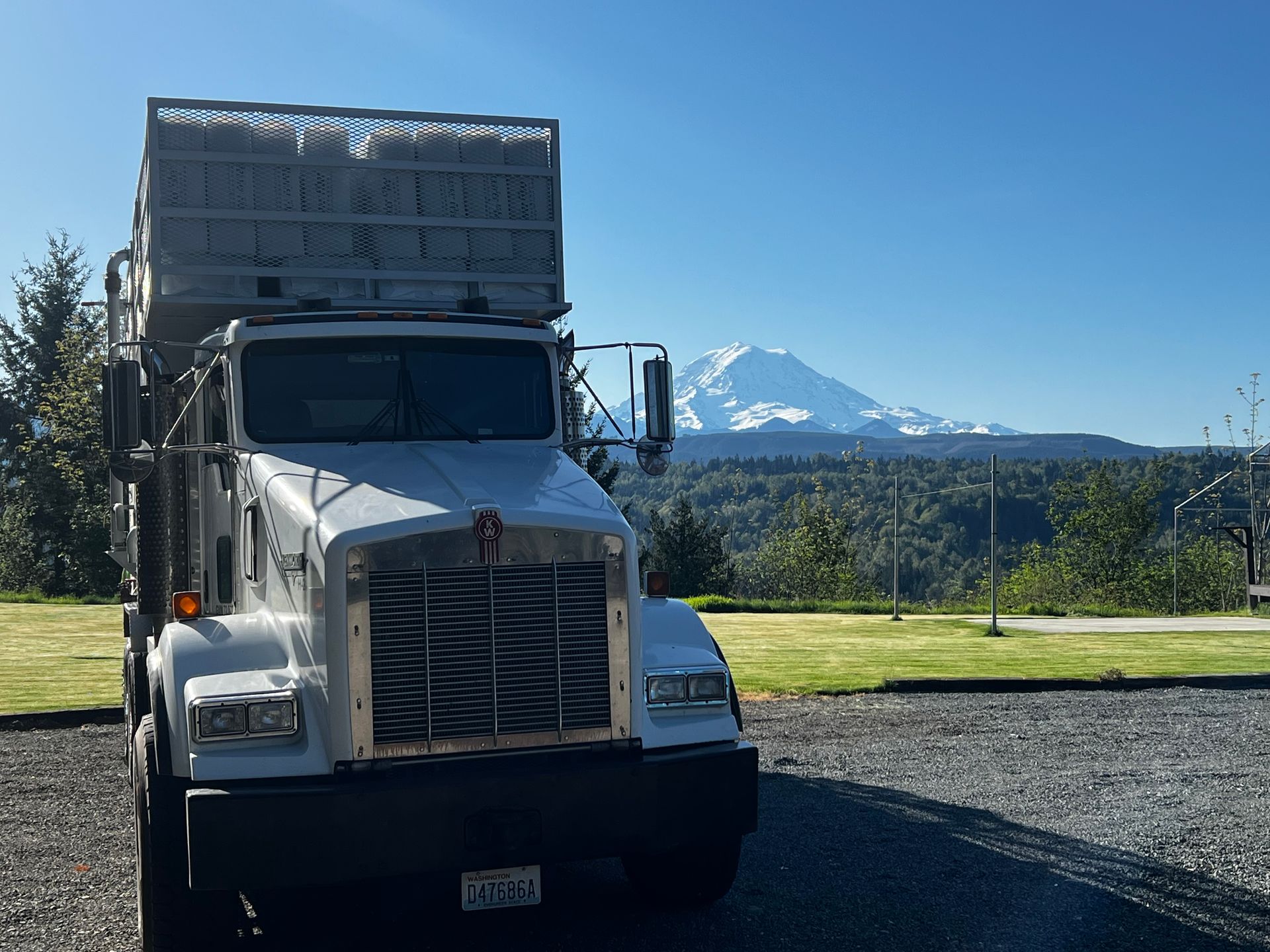 White semi-truck parked on gravel with snow-capped mountain in the background