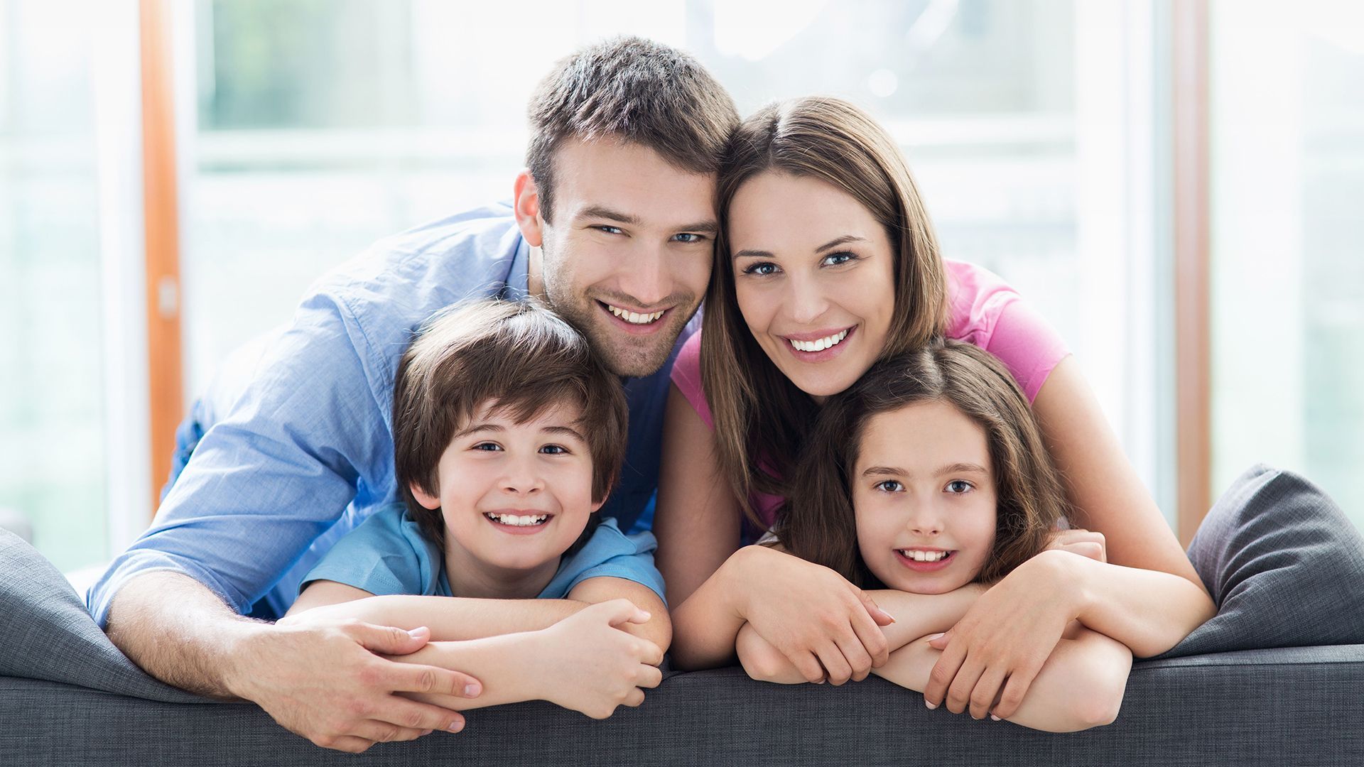 A family is posing for a picture while laying on a couch.