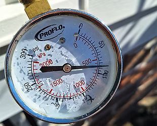 A close up of a pressure gauge on a hose.
