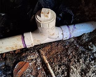 A white pipe is laying in the dirt on the ground.