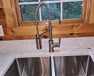 A kitchen sink with a stainless steel faucet and a window.