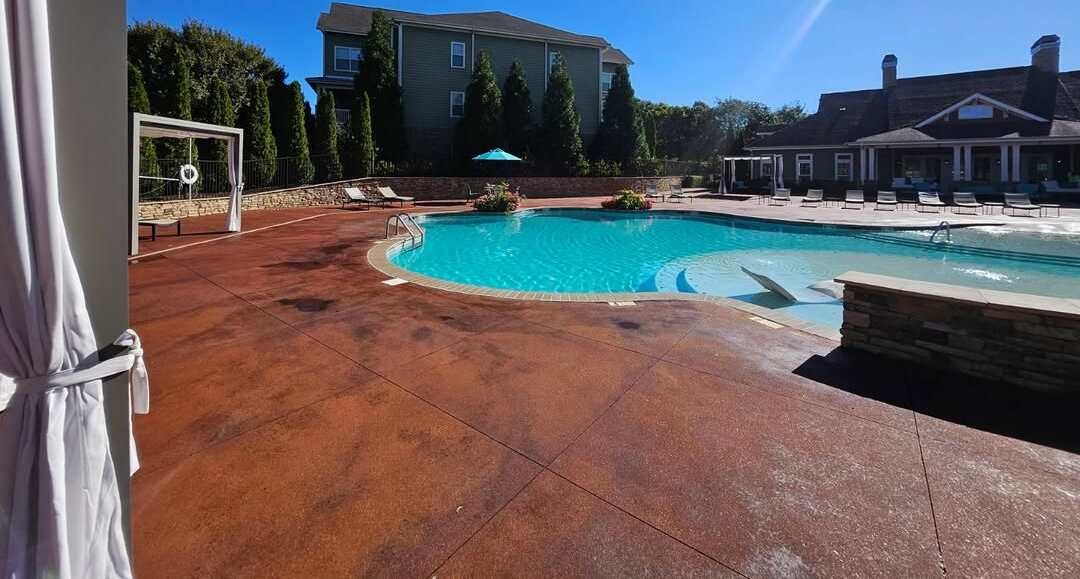 Person kneels, smoothing gray epoxy floor with a trowel, wearing gloves.