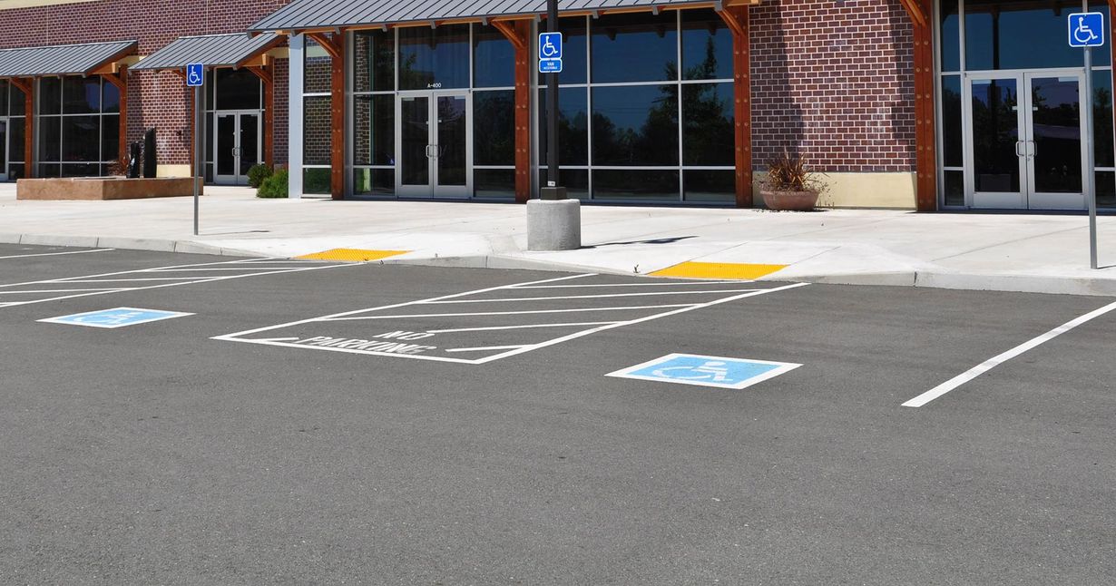 Two workers leveling wet concrete sidewalk with a screed.