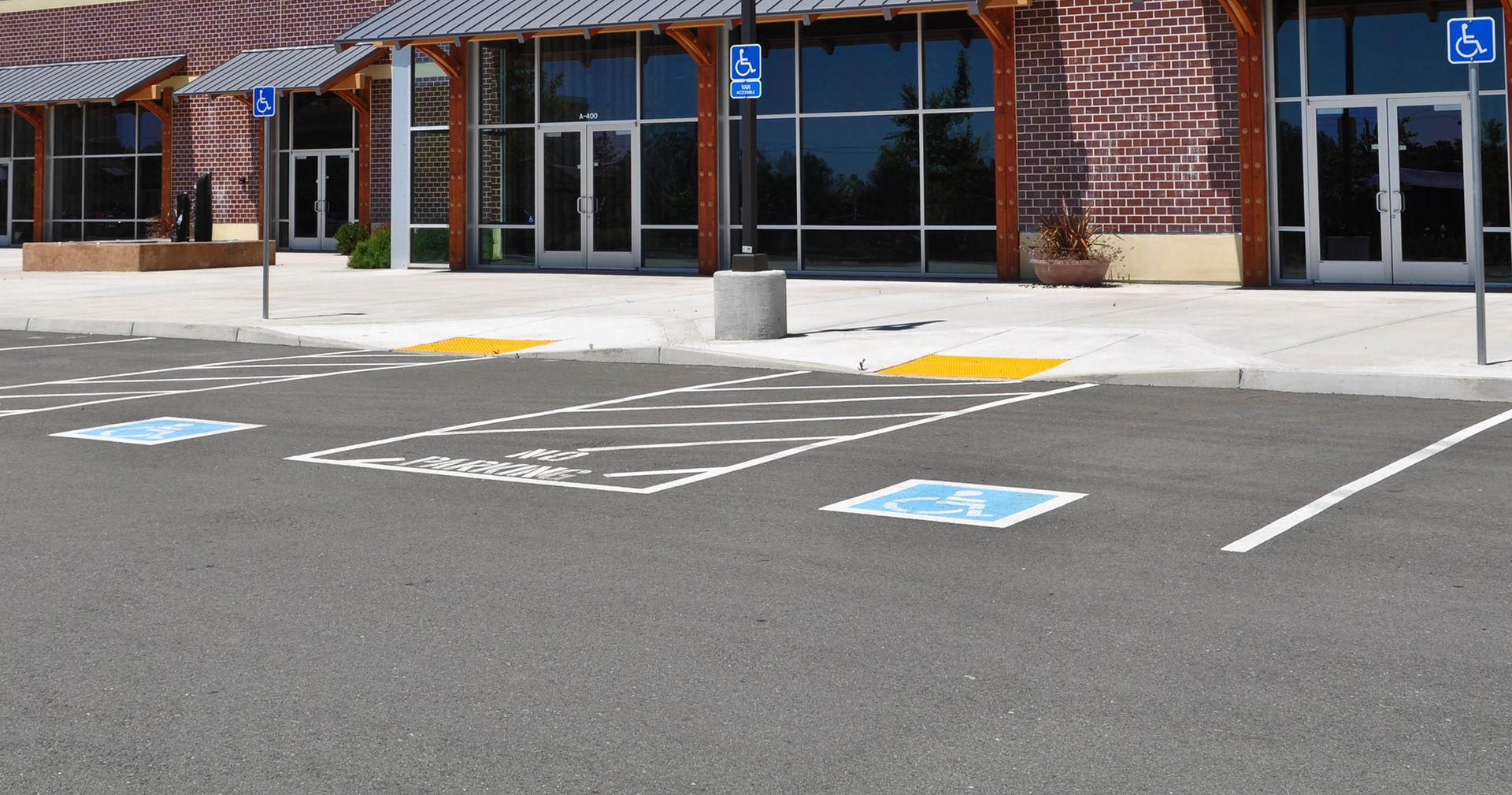 Two workers leveling wet concrete sidewalk with a screed.