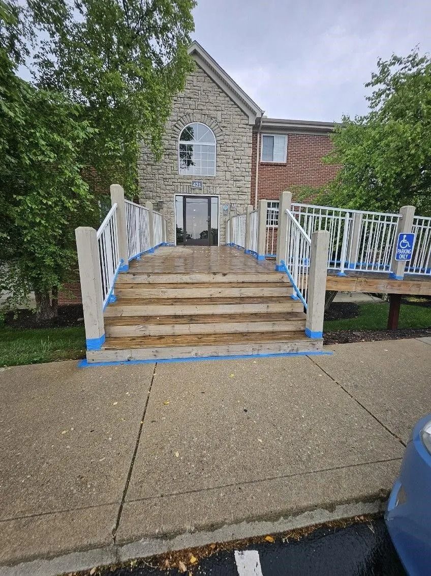 Stone building with steps, railing and accessible ramp entrance.