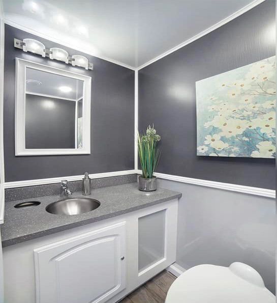 A bathroom with a sink, toilet, mirror, and painting on the wall.