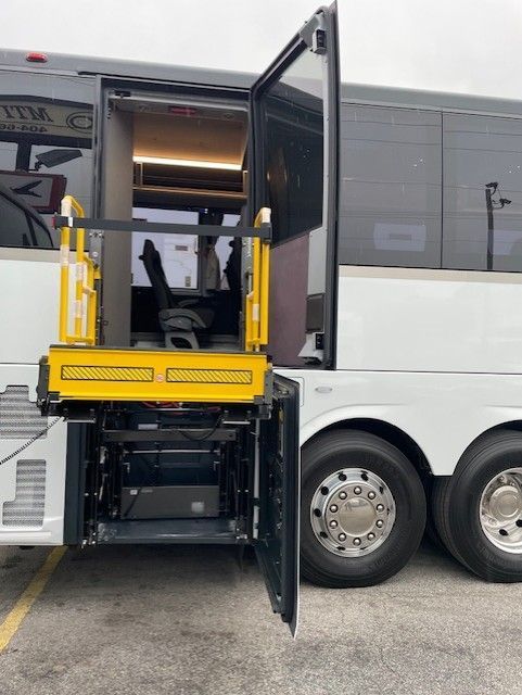 A white shuttle bus with open door revealing a yellow wheelchair lift.