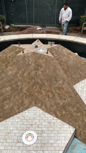 A person stands by a star-shaped tiled pool feature with light fixtures installed in the center and on one point.