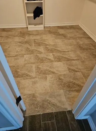 A small room with light-colored, rectangular tiled flooring and a white shelving unit against the far wall.