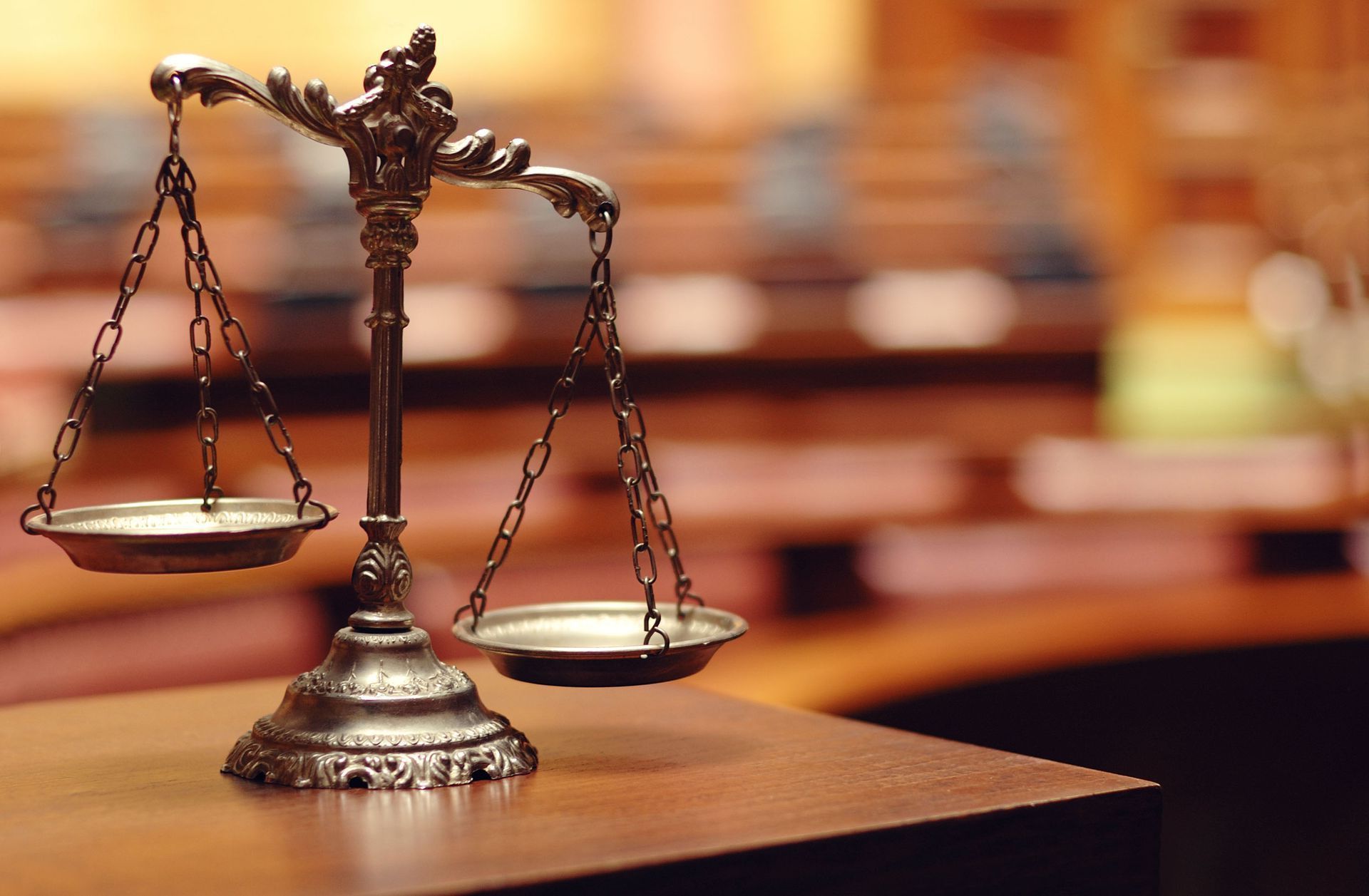 Antique balance scale on a wooden desk in a courtroom.