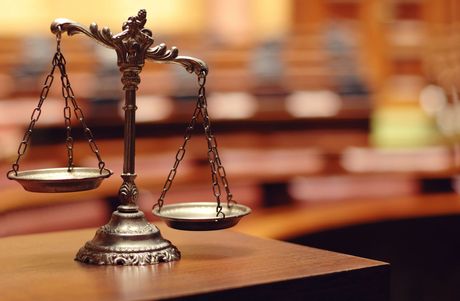 Antique balance scale on a wooden desk in a courtroom.