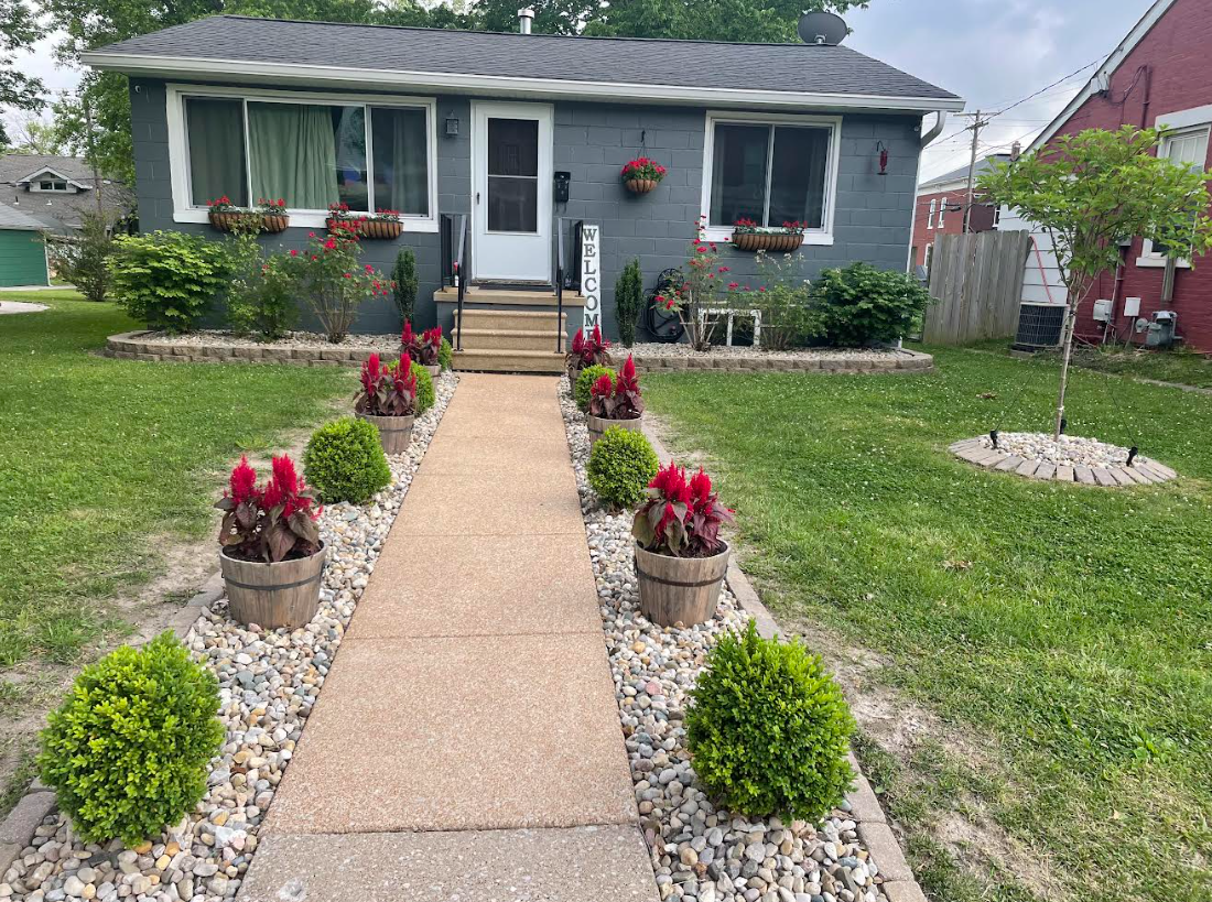 A house with a walkway leading to it decorated with flowers and rocks.