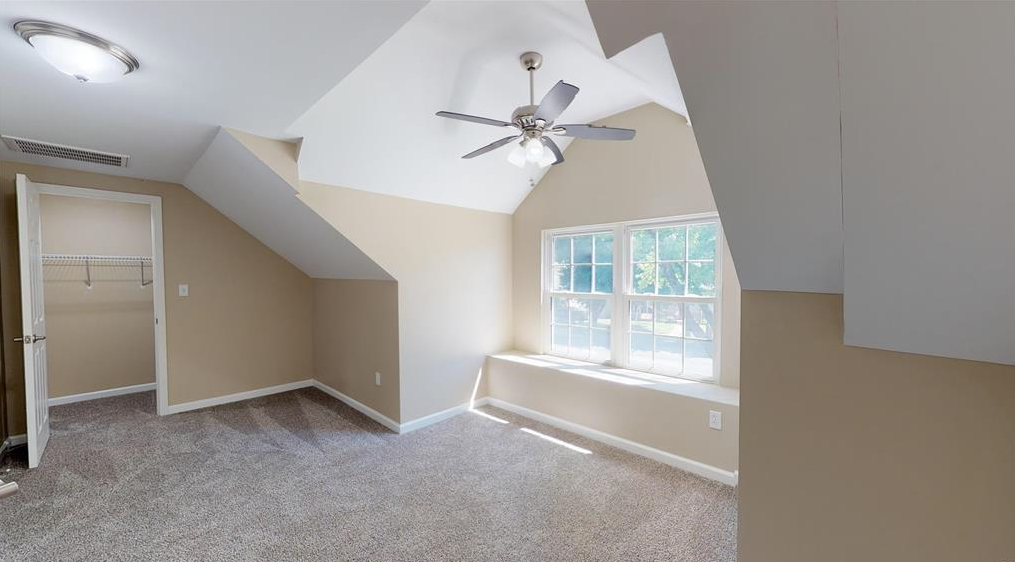 An empty bedroom with a ceiling fan and a window.
