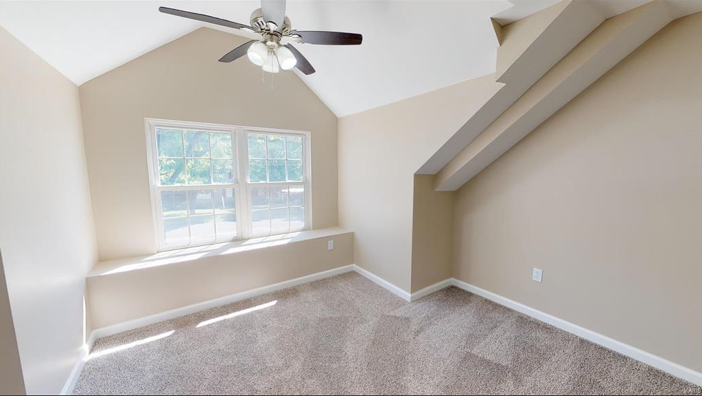 An empty room with a ceiling fan and a window