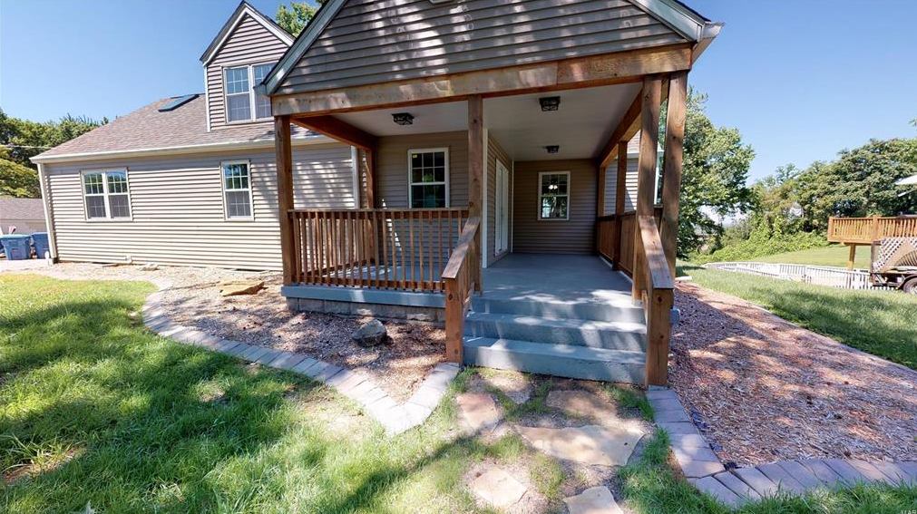 A small house with a porch and stairs in front of it.