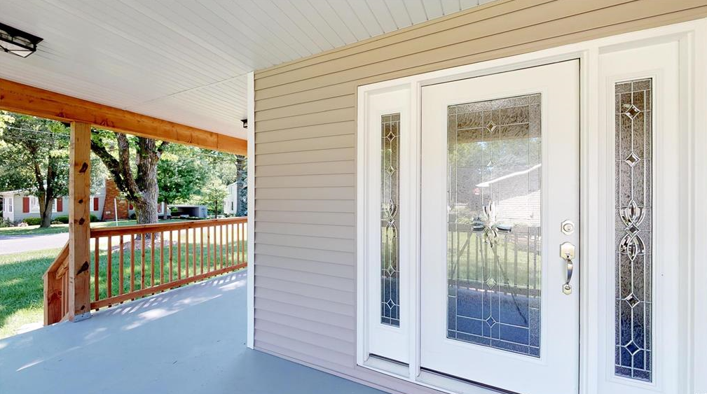 A porch with a white door and a wooden railing.