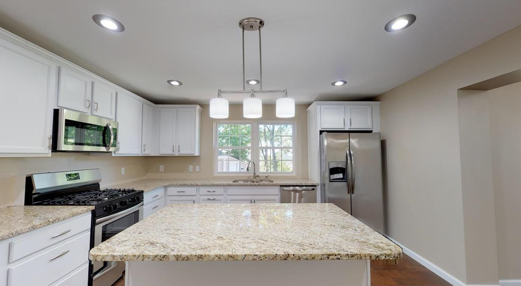 A kitchen with granite counter tops , stainless steel appliances , and white cabinets.
