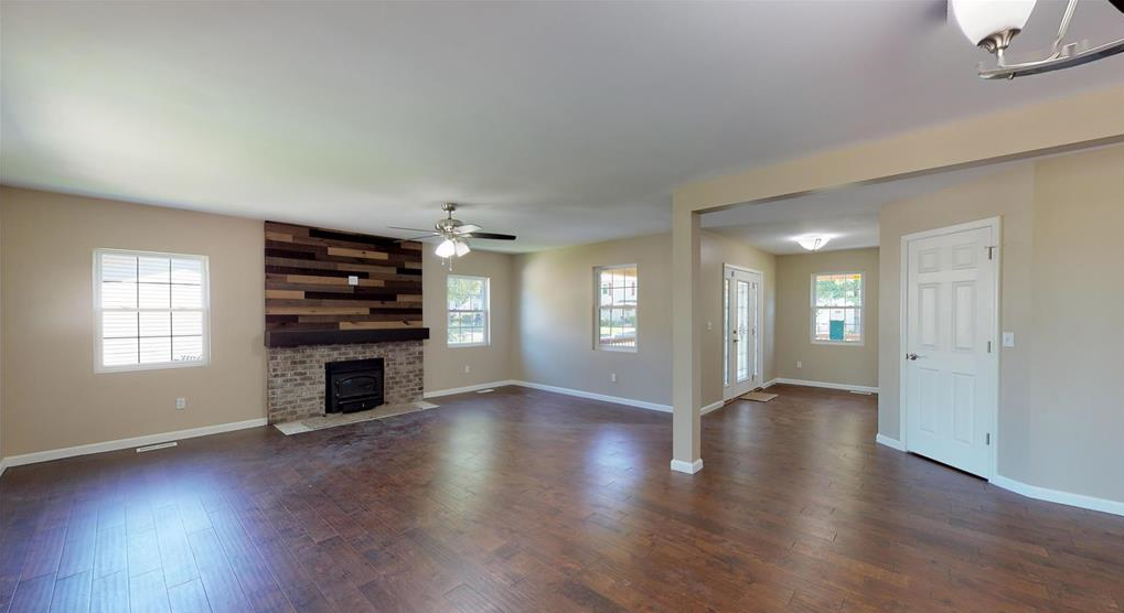 An empty living room with hardwood floors and a fireplace.